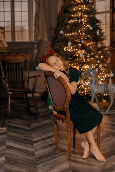 青いドレスの少女がクリスマスツリーのポーズをとっている 新年の広告 新年の装飾付きの写真スタジオ ガーランドで飾られたクリスマスツリー 選択的フォーカス フォーカス解除 — ストック写真