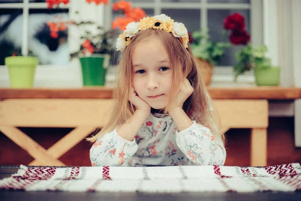 Uma Menina Sorridente Senta Uma Mesa Contra Pano Fundo Flores — Fotografia de Stock
