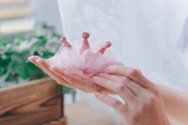 Kız elinde bir taç şeklinde pembe bir çocuk saçı kravatı tutuyor. Güzellik ve moda konsepti.