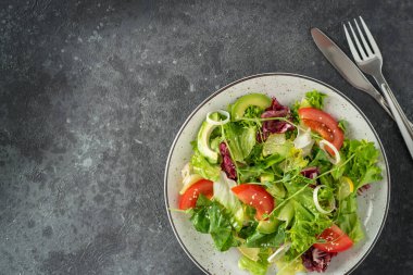 Koyu taştan arka planda taze vejetaryen salatası. Üst görünüm, alanı kopyala.
