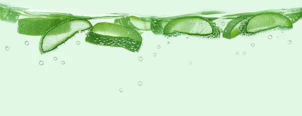Aloe vera slices under water on green background. Copy space, banner. — Stok Foto