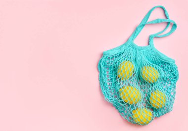Limonlar pembe arka planda ağ torbasında. Sıfır atık.