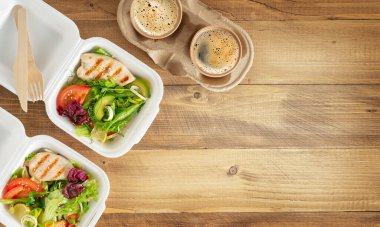 Salatalı beslenme çantası, ızgara tavuk ve ahşap masada kahve. Boşluğu kopyala, üst görünüm.