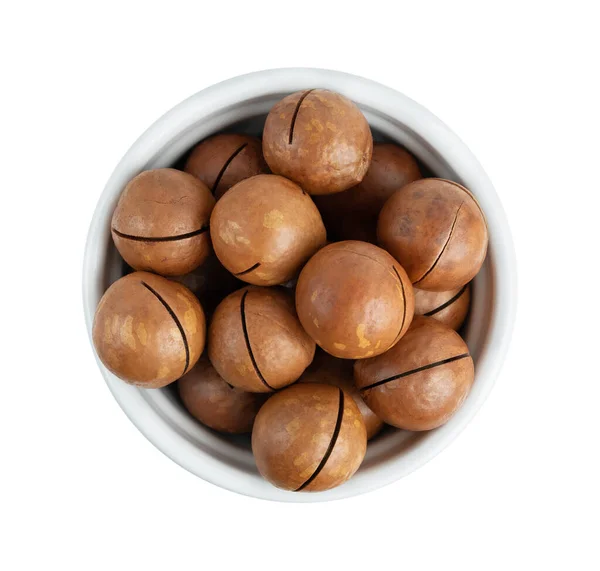 Macadamianötter i en skål på vit bakgrund. Ovanifrån — Stockfoto