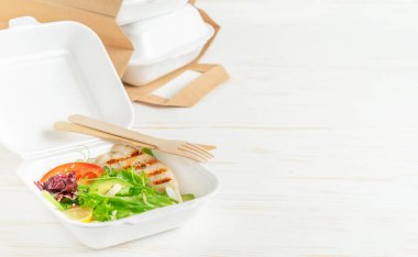 Yemek teslimatı, beyaz ahşap arka planda salatalı beslenme çantası.. 