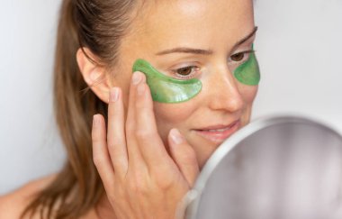 Beautiful young woman applying aloe vera eye patches. Skin care concept. High quality photo