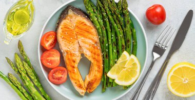Grilled trout steak and asparagus with ingredients on grey background. Directly above