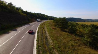 Aerial View Of Couple Driving Red Convertible Sports Car Down Country Road At Sunset . High quality 4k footage