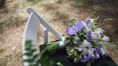 Wedding decor on the chairs , ribbons and flower on white chairs , wild flowers in small vases in the wedding decor. High quality FullHD footage