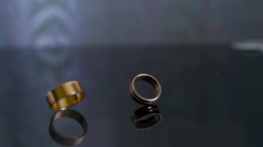 Close-up of two gold wedding rings. Brides rings rotates in slow motion on the mirror table. High quality FullHD footage