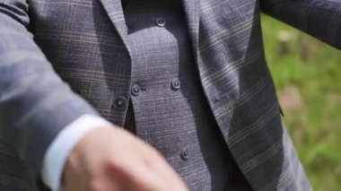 Closeup man hands with wrist watch in park. Getting better sleeves outdoors. Unrecognizable rich man buttoning up shirt sleeve under arch in garden. High quality FullHD footage
