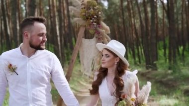 Middle shot. Young couple walking holding hands hugging in autumn forest. After wedding ceremony. High quality FullHD footage