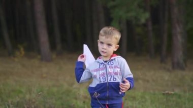 Child launching paper plane outdoor. Kid playing with a paper plane in the park. Slow motion. High quality FullHD footage