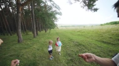 Wide Shot. Camera movement on running happy child with colourfull ball on green lawn in summer park at sunset. Little girl plays and laughs outdoors. Sport concept. High quality FullHD footage