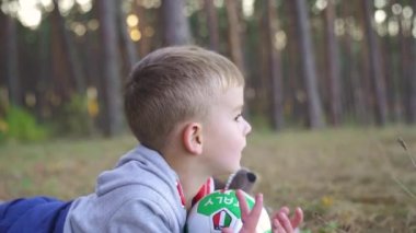 baby boy play ball in the park on sunset. Kid dream concept. kid baby play football soccer in nature park. baby kicking the ball running down fun the road in the park. Slow motion. FullHD footage