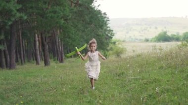 A girl runs with an airplane in her hands. Funny girl with her brother. Child Game. The girl dreams of becoming a pilot. Home video. Slow motion. High quality FullHD footage