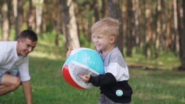 Slow motion. Happy little boy runs with a colorful ball in the park. Small brother and sister having fun playing with a ball. Fun dream kid concept. High quality FullHD footage