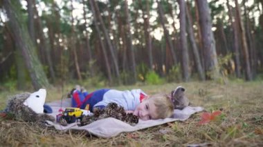 cheerful little baby boy plays with cones and other toys on carpet in the wood. Slow motion. High quality FullHD footage