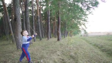Little boy playing with wood stick outside. Walking in the pine forest. Slow motion. High quality FullHD footage