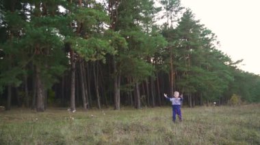 Child launching paper plane outdoor. Kid playing with a paper plane in the park. Slow motion. High quality FullHD footage