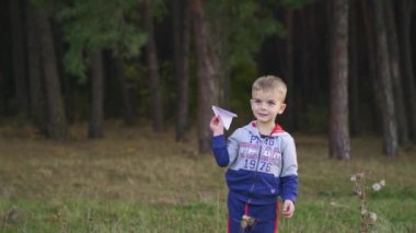 Child launching paper plane outdoor. Kid playing with a paper plane in the park. Slow motion. High quality FullHD footage