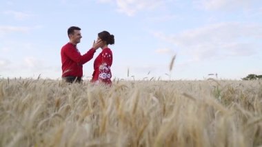 Couple in love at sunset in wheat. Red clothing. Slow motion. High quality FullHD footage