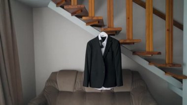 Mens suit on a hanger hanging on the wooden stairs. Moving camera. High quality FullHD footage
