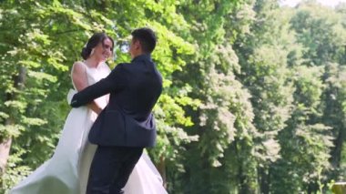 bride spinning groom holding her in his arms in the park. High quality FullHD footage