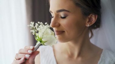Portrait cute young female posing with flowers in her hands. Wedding photo session of charming sensual bride under veil. Pretty stylish caucasian woman. Bridal day concept. High quality FullHD footage