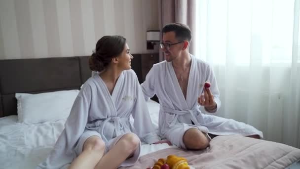 Happy Lovely Couple Dressed Bathrobes Lying Together Bed Eating Fruits — Stockvideo
