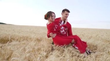 Young man kissing and spinning his girlfriend around on sunset in wheat field. Slow motion. High quality FullHD footage