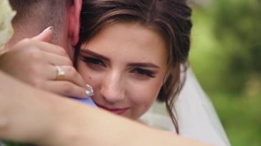 Güzel gelin ve damat birbirlerine gülümseyerek sarılırlar. Yeni evli çiftler yüz yüze sarılırlar. Gülümseyen düğün partnerleri birbirlerine sarılıyorlar. Neşeli çift damadı kucaklıyor. Yüksek kaliteli FullHD görüntüler