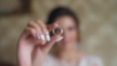 Gelin ringden bakıyor. Gelin odasında duruyor ve pencereden nikah yüzüğünden bakıyor. Yüksek kaliteli FullHD görüntüler