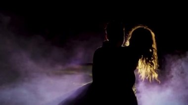 Genç çift dumanla karanlık bir alanda dans ediyor. Ağır çekim. Siluet. Yüksek kaliteli FullHD görüntüler