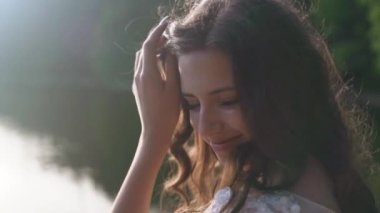 Kız dönüp kameraya bakıyor. Uzun kahverengi saçlı güzel bir kadın. Uçan kıvırcık saçlı çekici bir manken. Güzel esmer kadın saçlarını sallıyor. Ağır çekim. Tam HD görüntüler