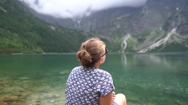 波兰Tatra国家公园 著名的高山湖莫尔斯基奥科湖或夏日晨曦中的海眼湖 全景多云的山峰 少女坐在石头上 高质量的4K镜头 — 图库视频影像