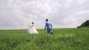 Yeni evliler birlikte yeşil alanda, dikiz aynasından koşuyorlar. Ağır çekim. Yüksek kaliteli FullHD görüntüler