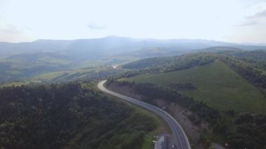 Dağlık yolun havadan görünüşü. Soğuk sonbahar dağları ve ormanda temiz bir yol. Vahşi dağ manzarasında otoyolun destansı insansız hava aracı görüntüleri. Çok yüksekten uçuyor. Yüksek kalite 4k görüntü