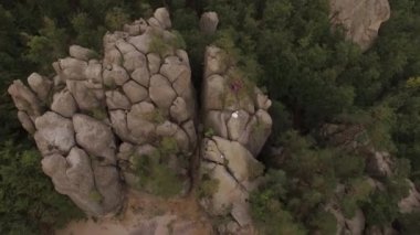 Ukrayna 'nın Karpat Dağları' ndaki Dovbush kayalarının hava manzarası. İnsansız hava aracı destansı kireçtaşı taşlarının üzerinden uçar. Yeşil orman ağaçları ve sık ağaçlar arasında kayalık kayalıklarla dolu parlak manzara yaz günbatımında.