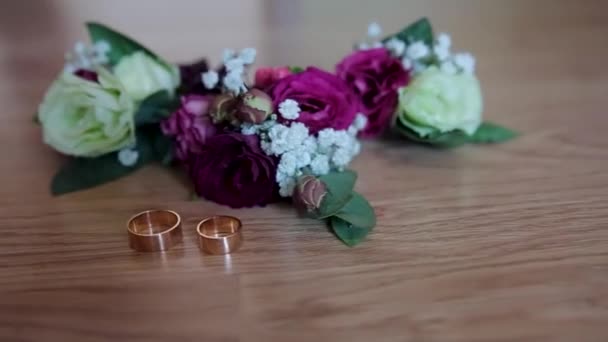 ベージュ色のみすぼらしいテーブルの上に貴重な鮮やかな婚約指輪と緑のバラの花のドリーショット プラチナリング ジュエリーコンセプト バレンタインデー 高品質のフルHd映像 — ストック動画