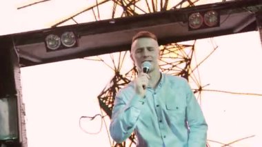 Rock konserinde sahne performansı sırasında mikrofonla şarkı söyleyen bir adam. Renkli ışık arka planında müzik konseri veren rock yıldızı şarkıcısını kapatıyoruz. Yüksek kalite 4k görüntü