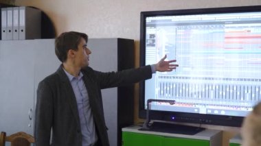 Ağır çekim. Erkek öğretmen boş bir sınıfta interaktif bir beyaz tahta kullanarak müzisyen programları öğretiyor. Yüksek kaliteli FullHD görüntüler