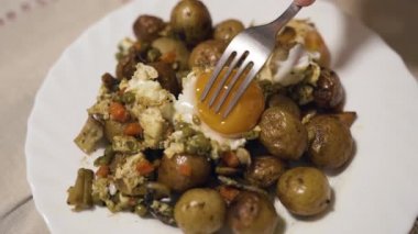 Ağır çekim. Çatal yumurta sarısını yok eder. İsveç yemeği A Bowl, yeşil bezelye, havuç. Klasik İsveç usulü patates, sahanda yumurta ve sebze. Tavayı kapat. Yüksek kaliteli FullHD görüntüler