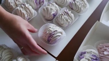 Bir kadın hediye kutusunda açık yeşil ve pembe şekerlemeler taşıyor. Paketleme için yakın aksesuarlar. Ev işi konsepti. Yüksek kalite 4k görüntü