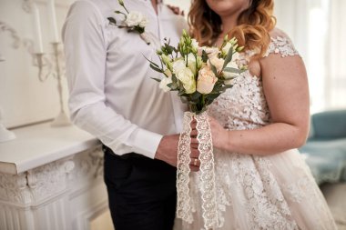 Gelin elinde bir buket ile damadın yanında duruyor.