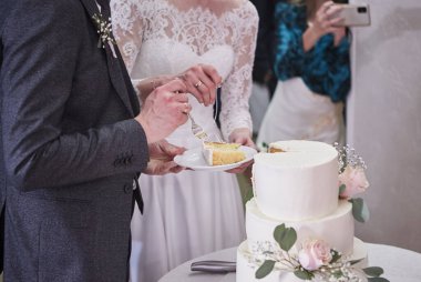 Ziyafette gelin ve damat birlikte düğün pastasını kestiler, bir bıçağa tutunarak. Düğün detayları yakın plan