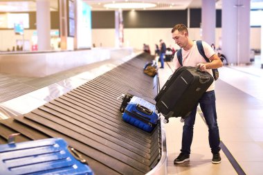 Bir erkek Avrupalı yolcu (yolcu) bagajını İstanbul Havalimanı 'ndaki Havnıani Uluslararası Havalimanı' ndan (IST Havalimanı) vardıktan sonra bagaj teslim kasetinden alır.)