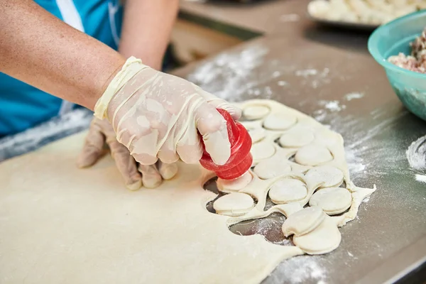 Şefin elleri arka planda el yapımı ravioli ve un serpiştirilmiş khinkali ile yapılan hamur tatlısı pişiriyor. Lezzetli ev yemekleri..