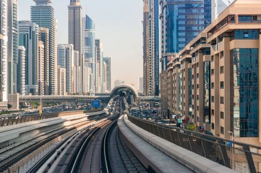 Dubai, Birleşik Arap Emirlikleri - 06 Kasım 2021: Dubai metrosu gökdelenlerin arka planında. Metro vagonundan şehrin manzarası.