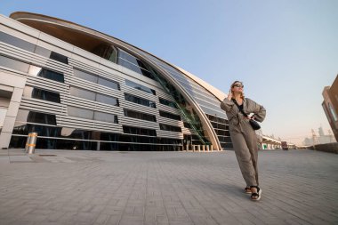 Kadın turist Dubai, BAE 'de arka plandaki metro istasyonunda duruyor. Geleceğin modern fütürist metrosu